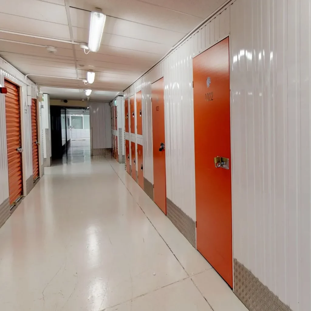 A long hallway with white walls and red doors at Elephant Click & Store facilities.