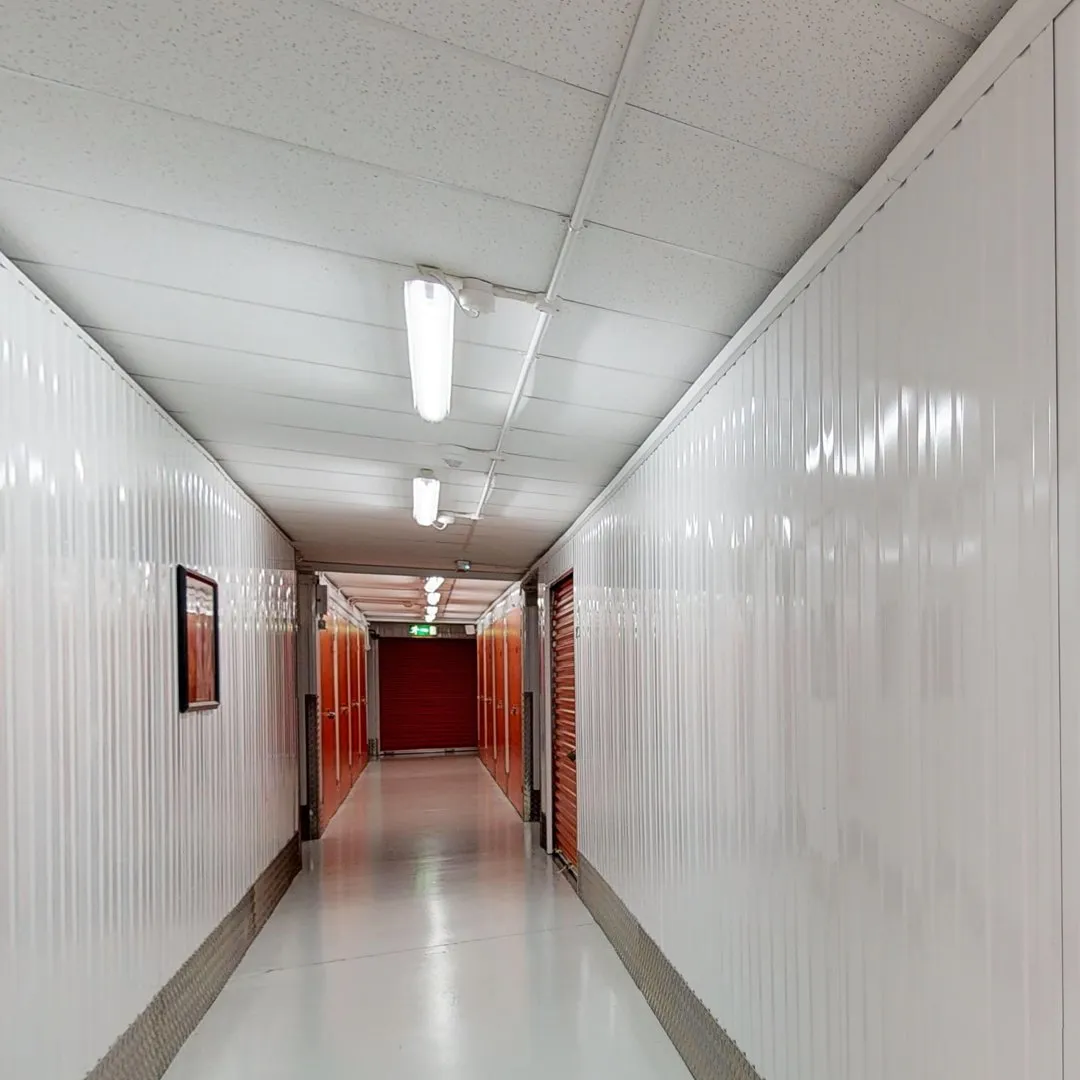 A long hallway with white walls and red doors at Elephant Click & Store facilities.
