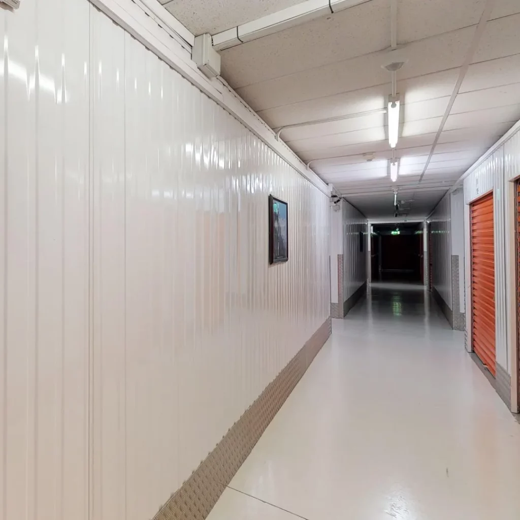 A long hallway with white walls and red doors at Elephant Click & Store facilities.