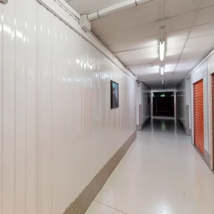A long hallway with white walls and red doors at Elephant Click & Store facilities.