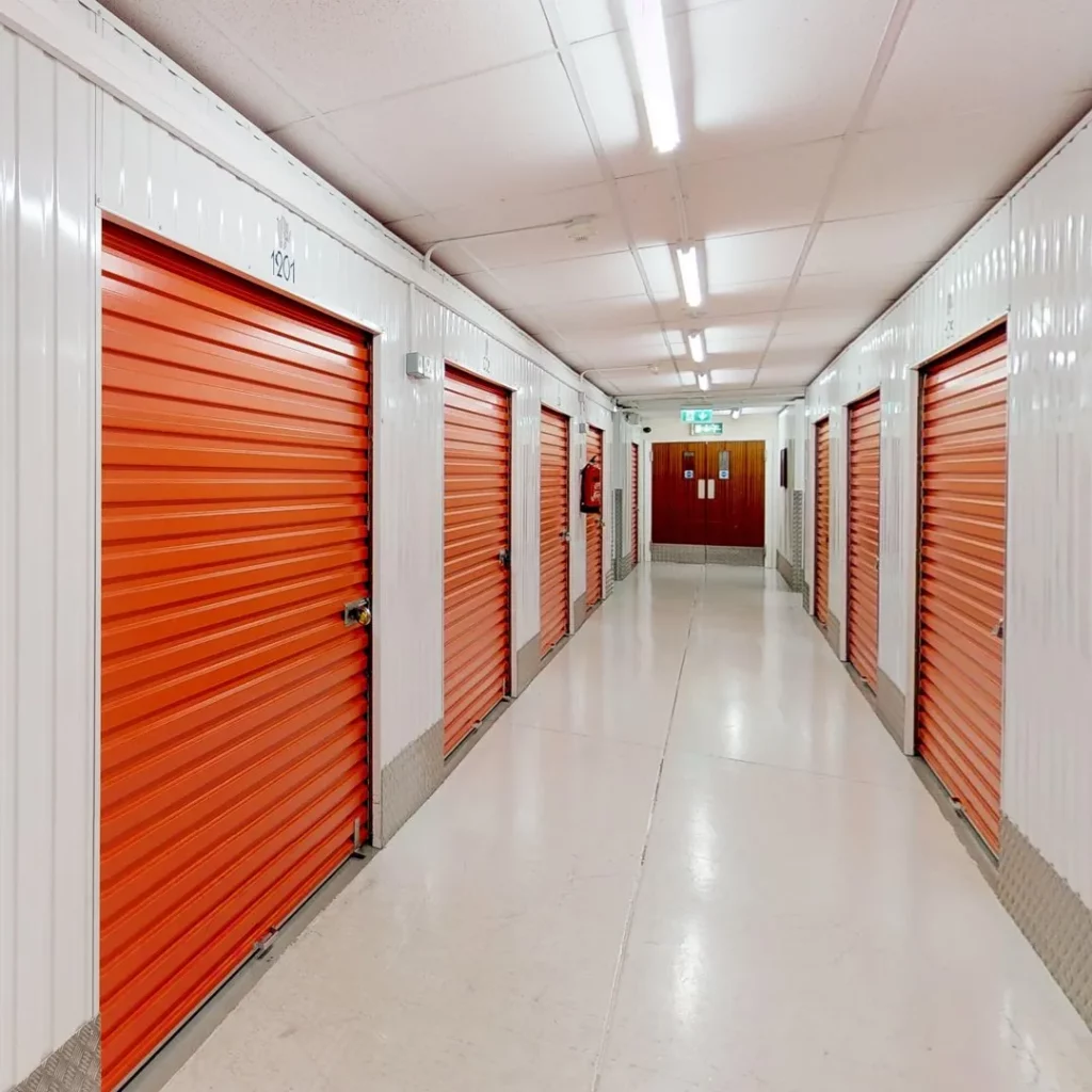 A long hallway with white walls and red doors at Elephant Click & Store facilities.