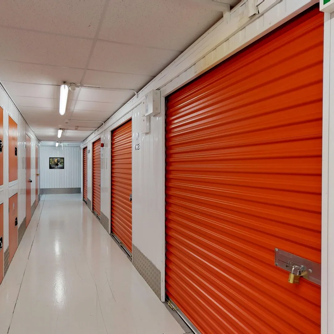 A long hallway with white walls and red doors at Elephant Click & Store facilities.