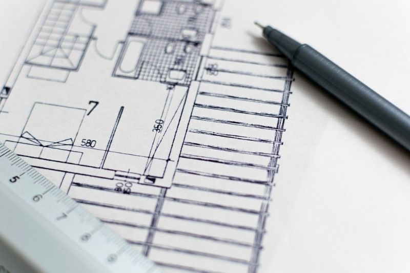 A ruler and pencil on top of a blueprint, tools for precise measurements and drafting plans.