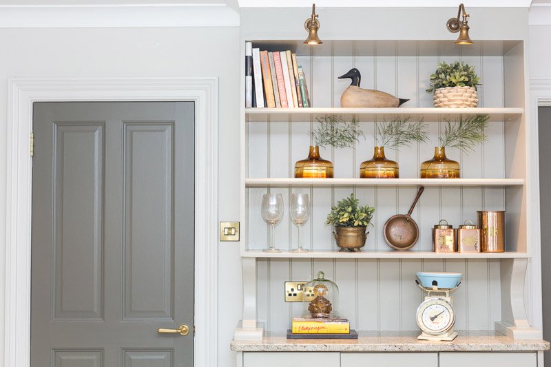 A kitchen with white cabinet and shelves, providing storage and a clean, minimalist look.