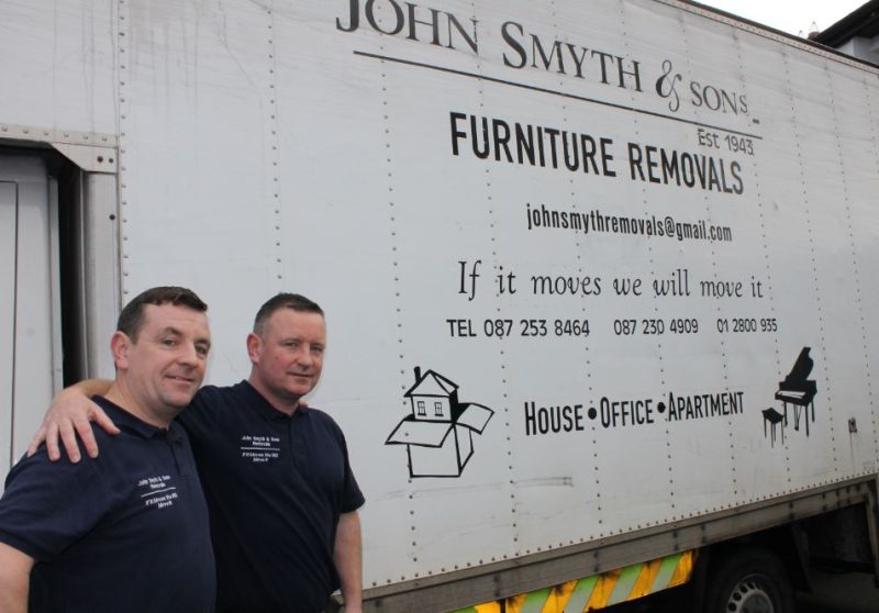 Two men standing in front of a furniture removal truck, ready to assist with moving services.