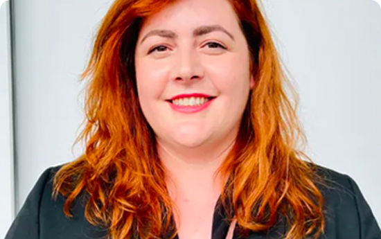 A woman with red hair wearing a black blazer.