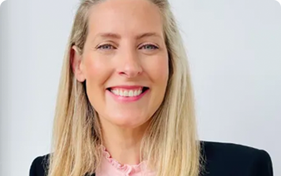 A woman with blonde hair wearing a pink shirt.