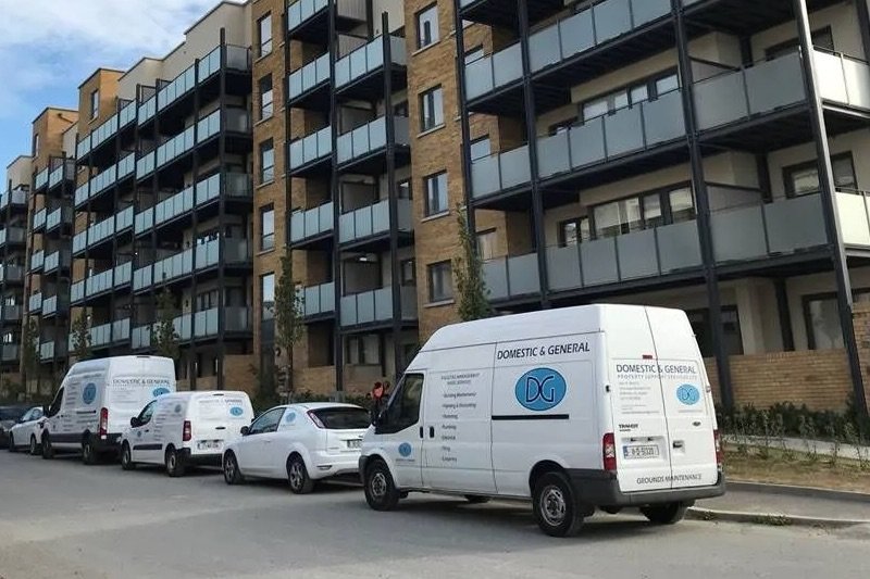 Several vans parked in front of an apartment building, representing a domestic and general cleaning service.